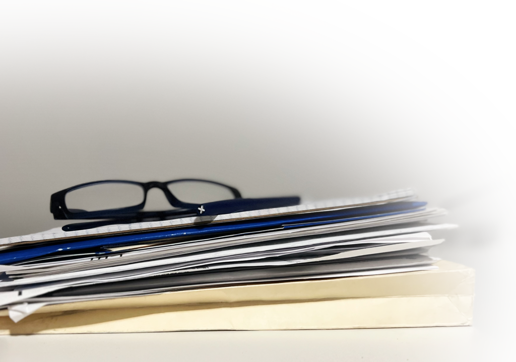 Image of reading glasses on stack of paperwork, case files, more information, studies