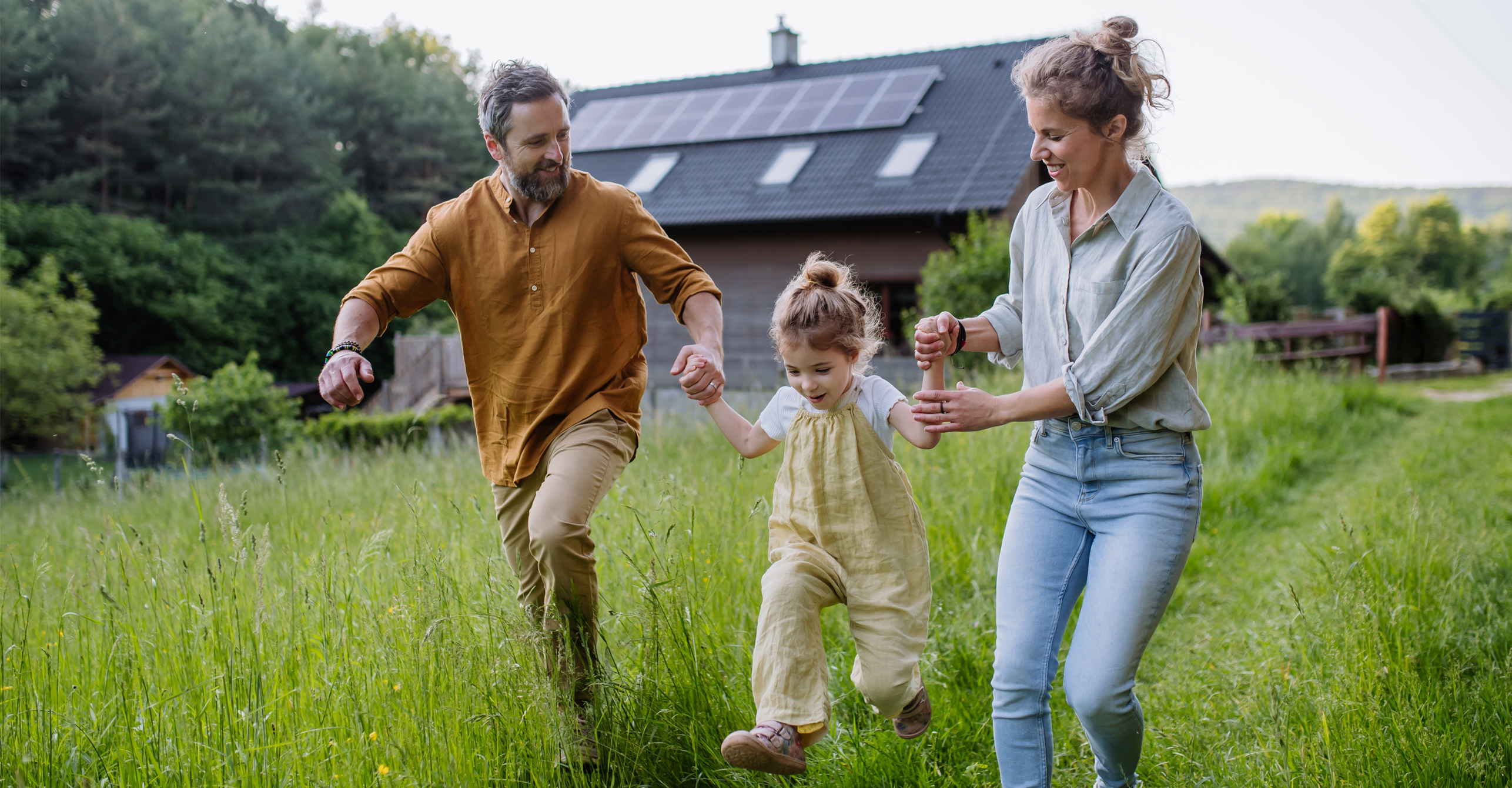 Families of wealth, family of three swinging small child, walking down grassy path away from home, nurturing, growth, values, middle aged parents