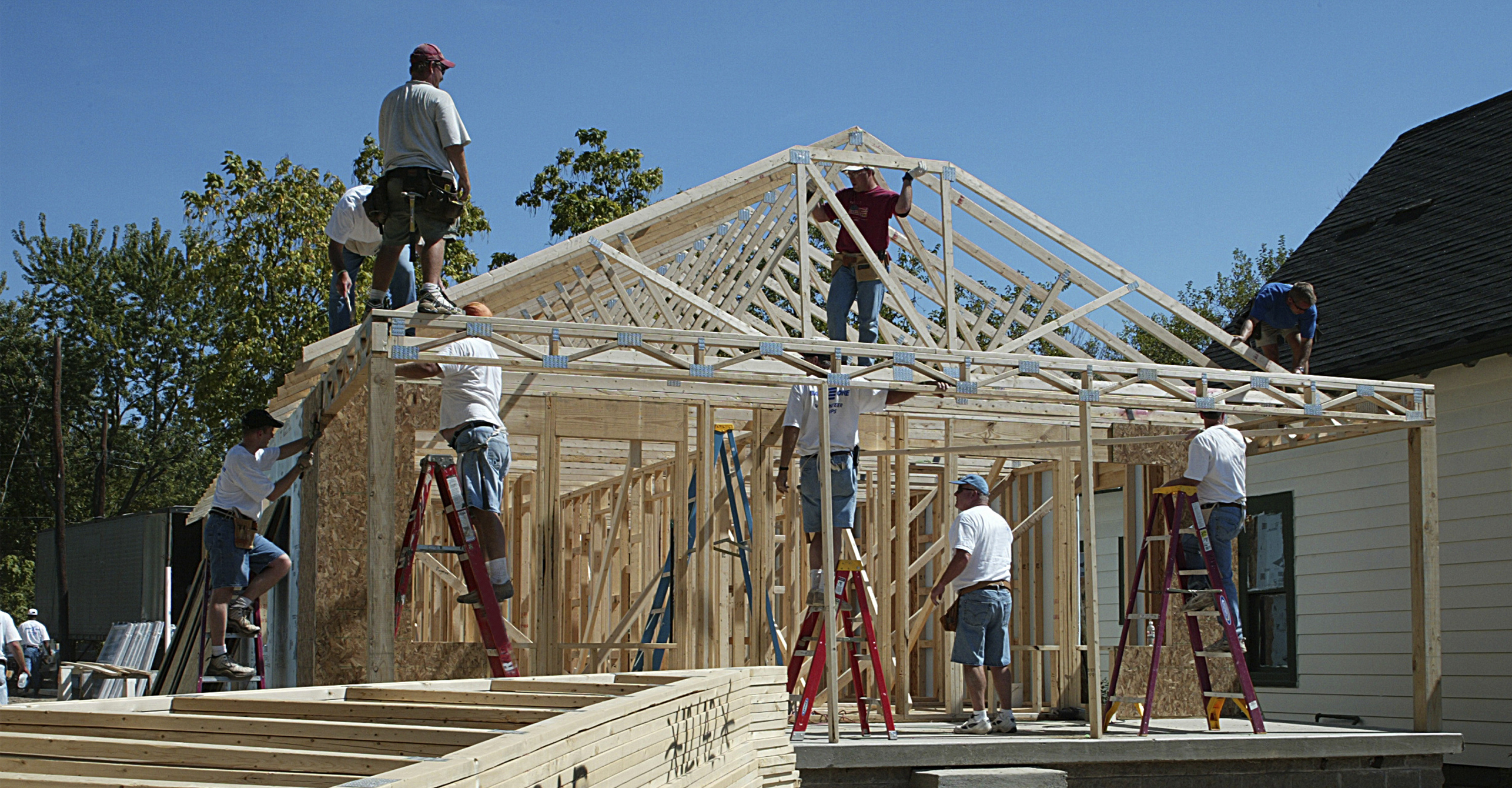 Community projects, volunteering, building a home, coming together, men on framework of house, project, contributing, philanthropy, giving back