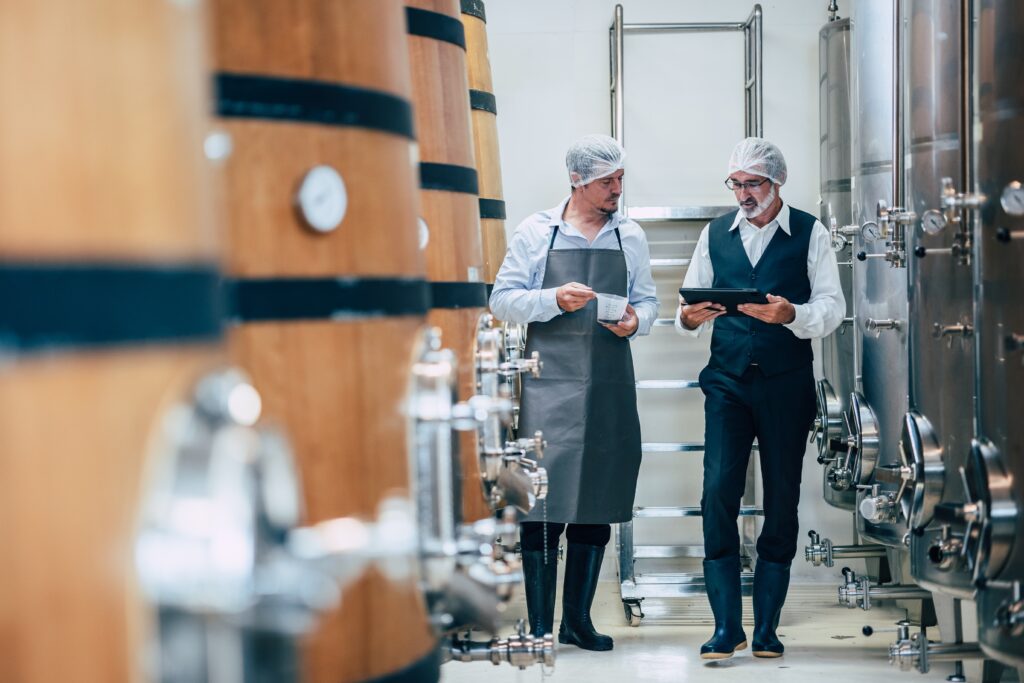 Vintners walking, winery, machinery, wine barrels, discussing business, strategy, family business, decision-making